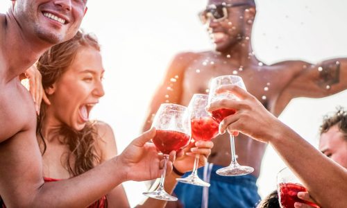 Happy friends drinking sangria wine at exclusive boat party - Young people having fun in summer vacation - Focus on left man hand glass - Travel, friendship, holidays and youth lifestyle concept